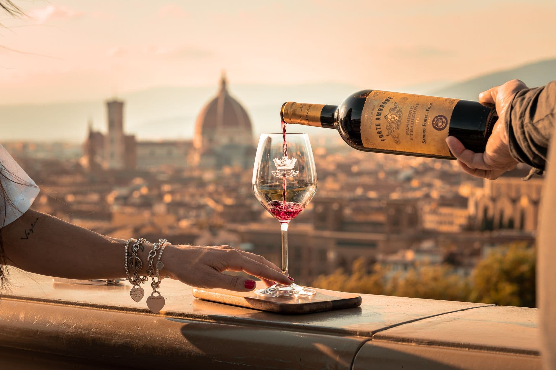 Verre de cannonau rouge et bouteille de mirto devant un vignoble sarde